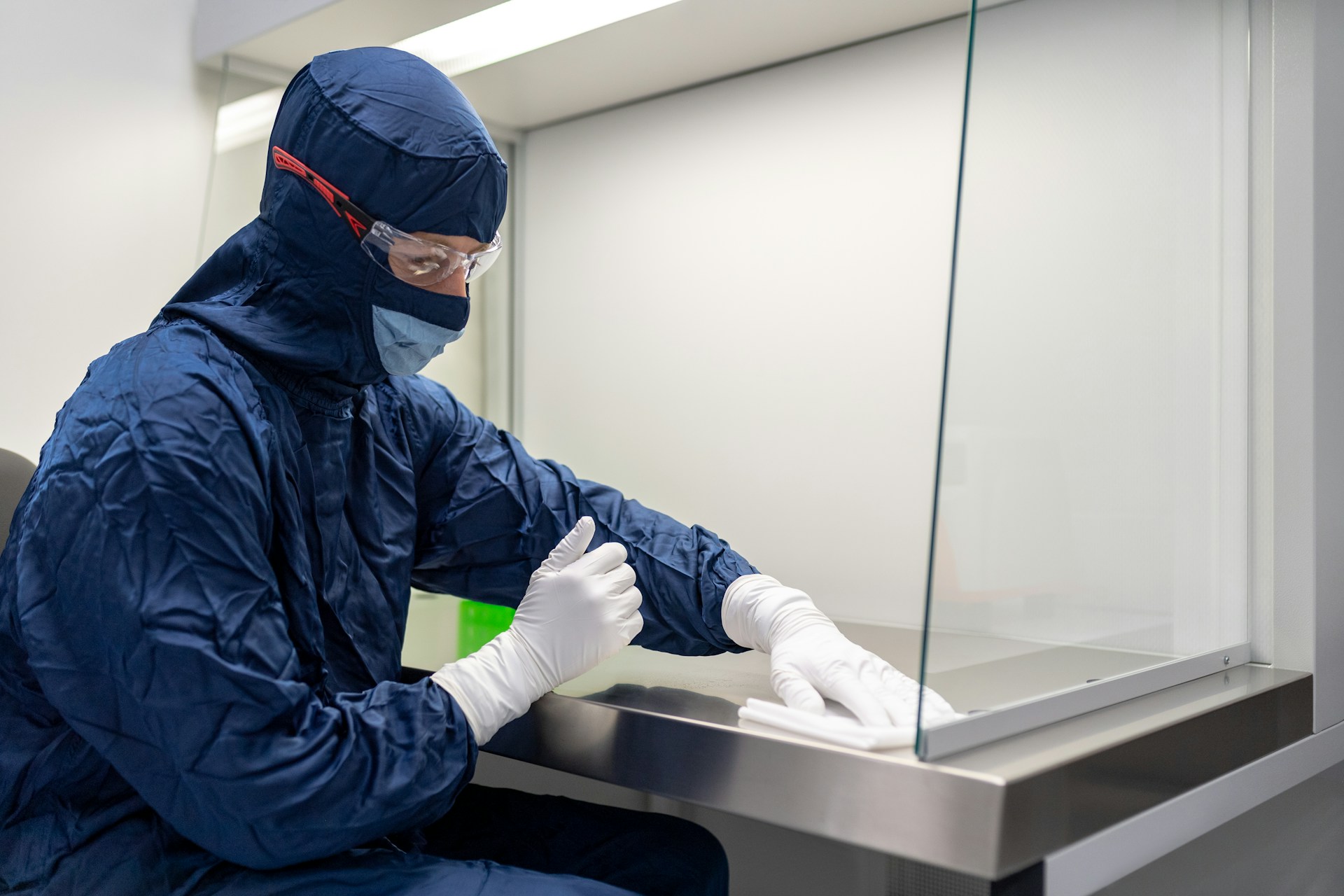 A technician wiping a cabinet with a cleanroom wiper 